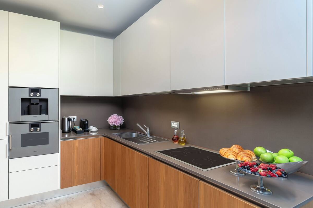A modern kitchen with built-in appliances, a sink, and a fruit bowl.