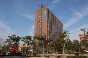 A tall hotel with a modern design, featuring a prominent blue sign on the top. - Wyndham Jinjiang (Quanzhou)