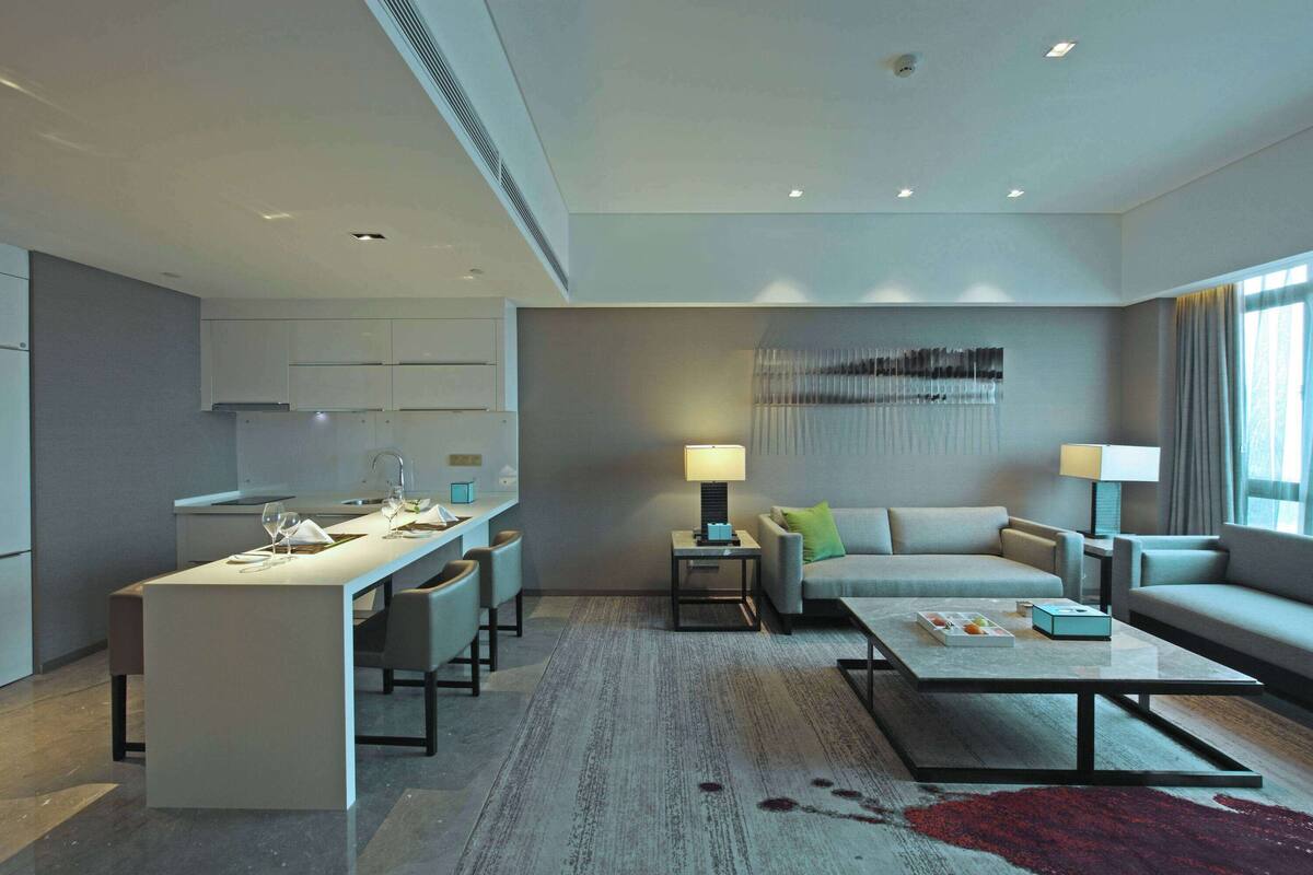 A modern living room with a sofa, coffee table, and a dining area with chairs and a table set for a meal.