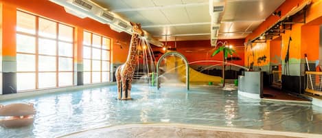 A large indoor pool with a giraffe statue, water features, and a slide.