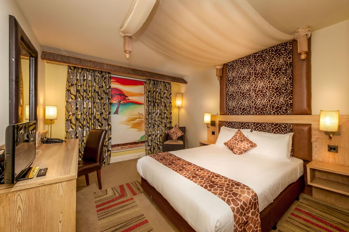A hotel room with a large bed, a desk with a computer, and a TV.