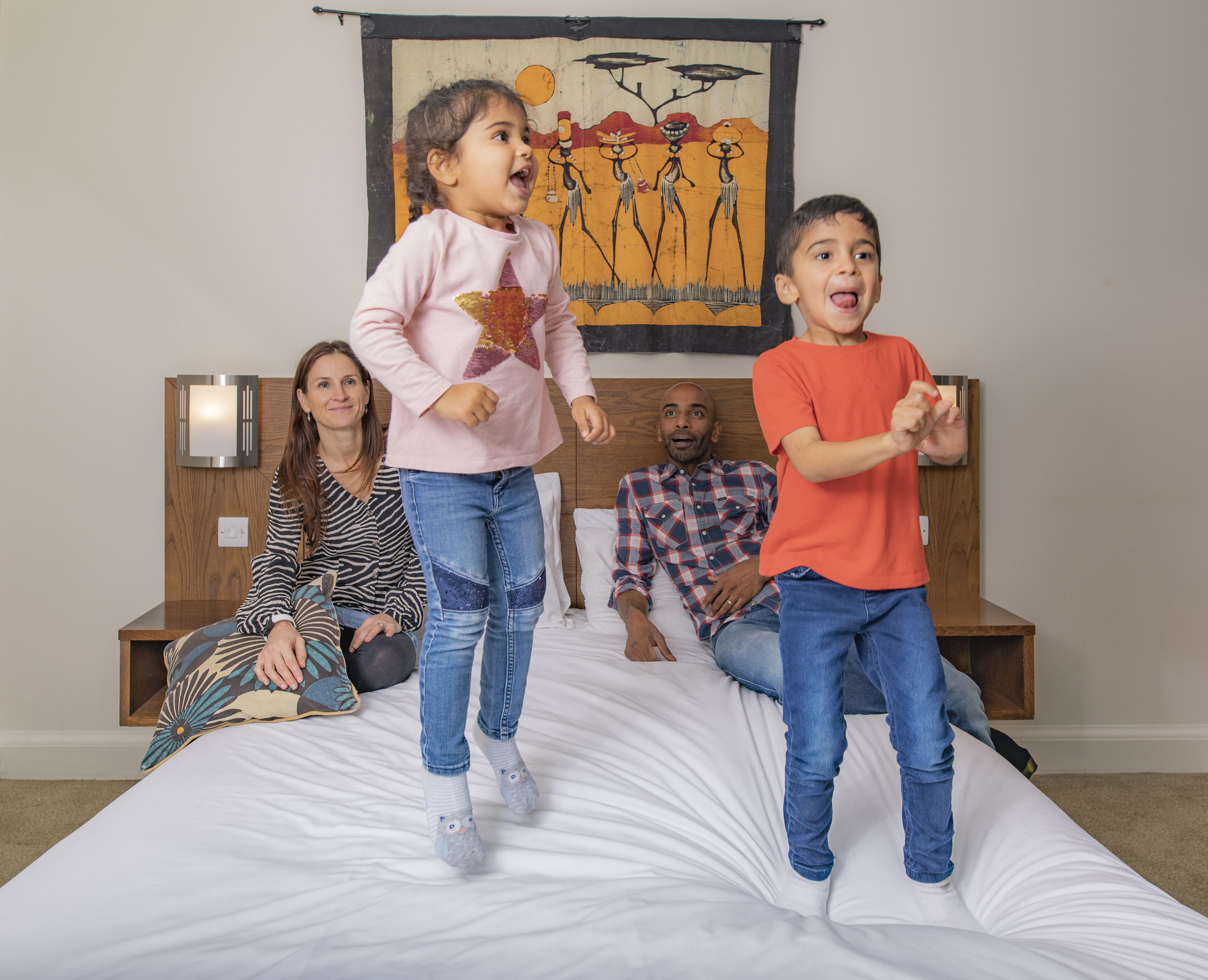 Un dormitorio con una cama, una obra de arte colgada en la pared y una mesita de noche con una lámpara.