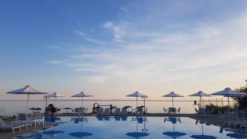 Alberca al aire libre, sombrillas en la alberca y camastros