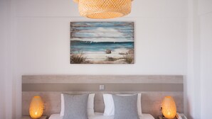 Un dormitorio con una cama, dos lámparas de noche, un cuadro de una playa y un cabecero de madera.