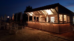 Zona de bar al aire libre con suelo de piedra, mostrador y asientos.
