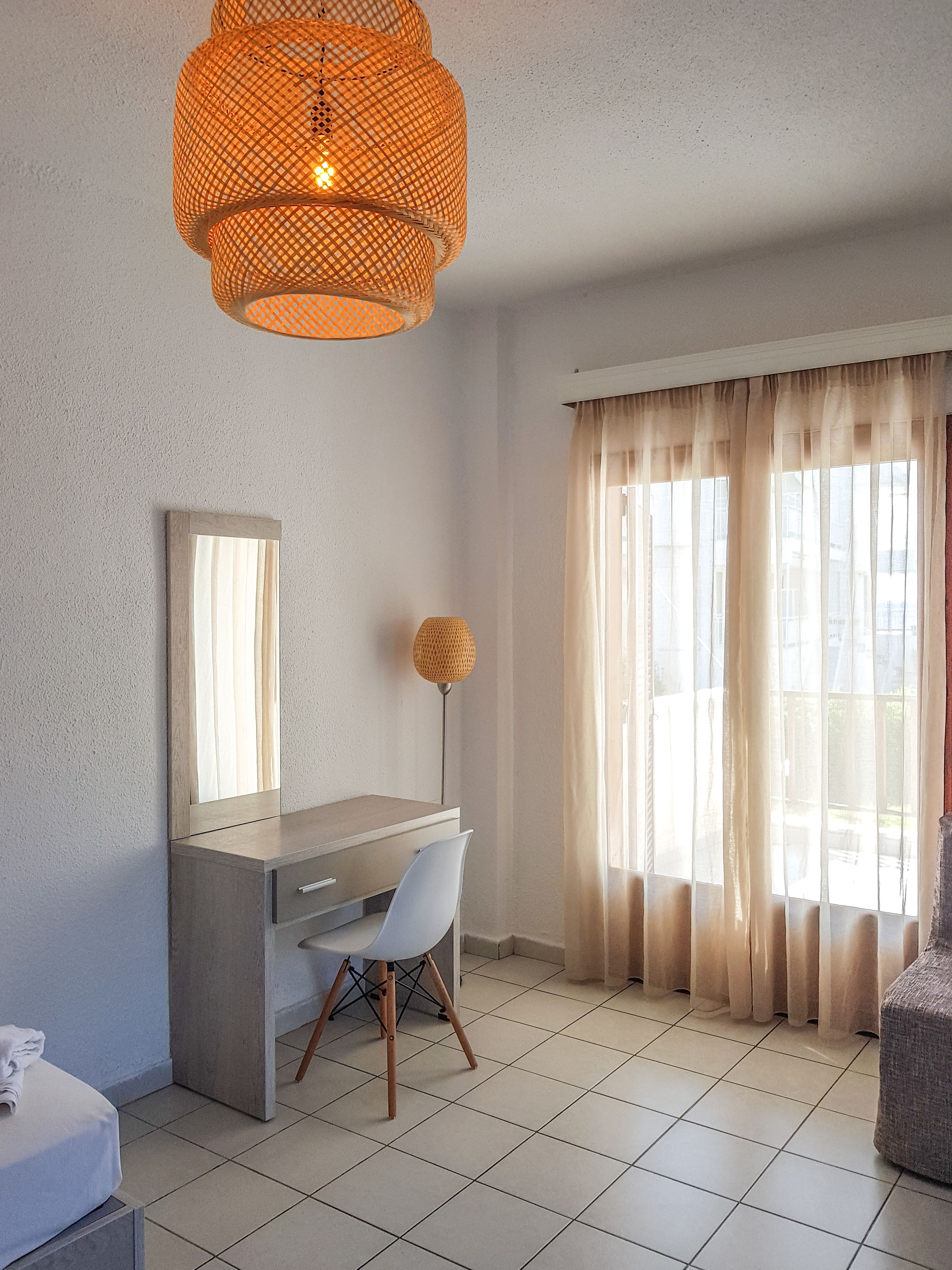 A modern room with a desk, chair, and a large window with curtains.