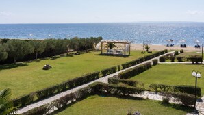 Un jardín ajardinado con un mirador, zonas de estar y vista al mar.