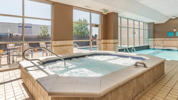 Una habitación de hotel con un ventanal grande, un jacuzzi y una zona de piscina.