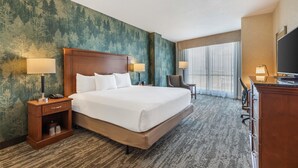Habitación de hotel con una cama grande, dos mesitas de noche con lámparas, un escritorio con silla y un televisor.