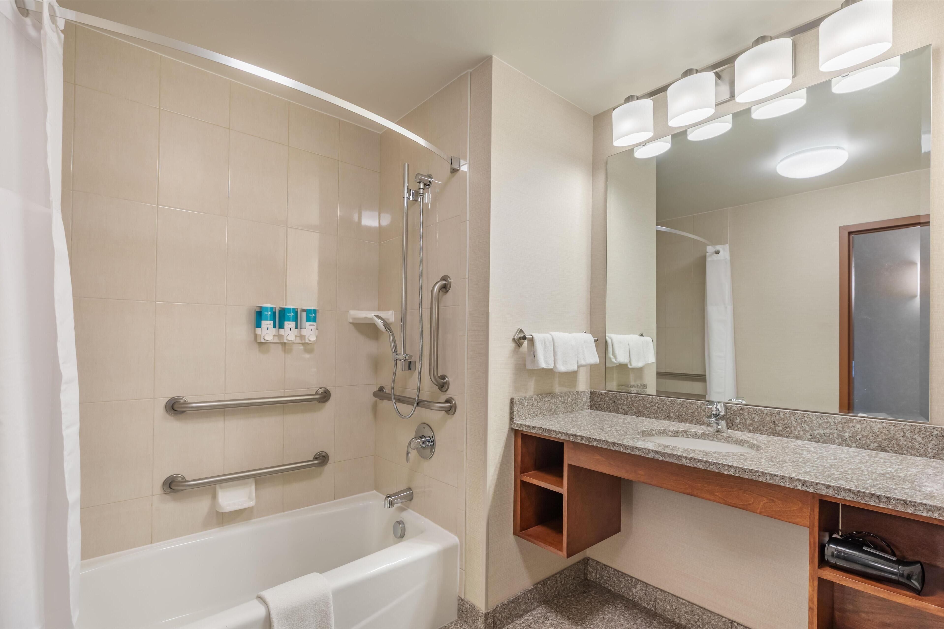 A modern bathroom with a bathtub, a shower, and a vanity with a mirror.