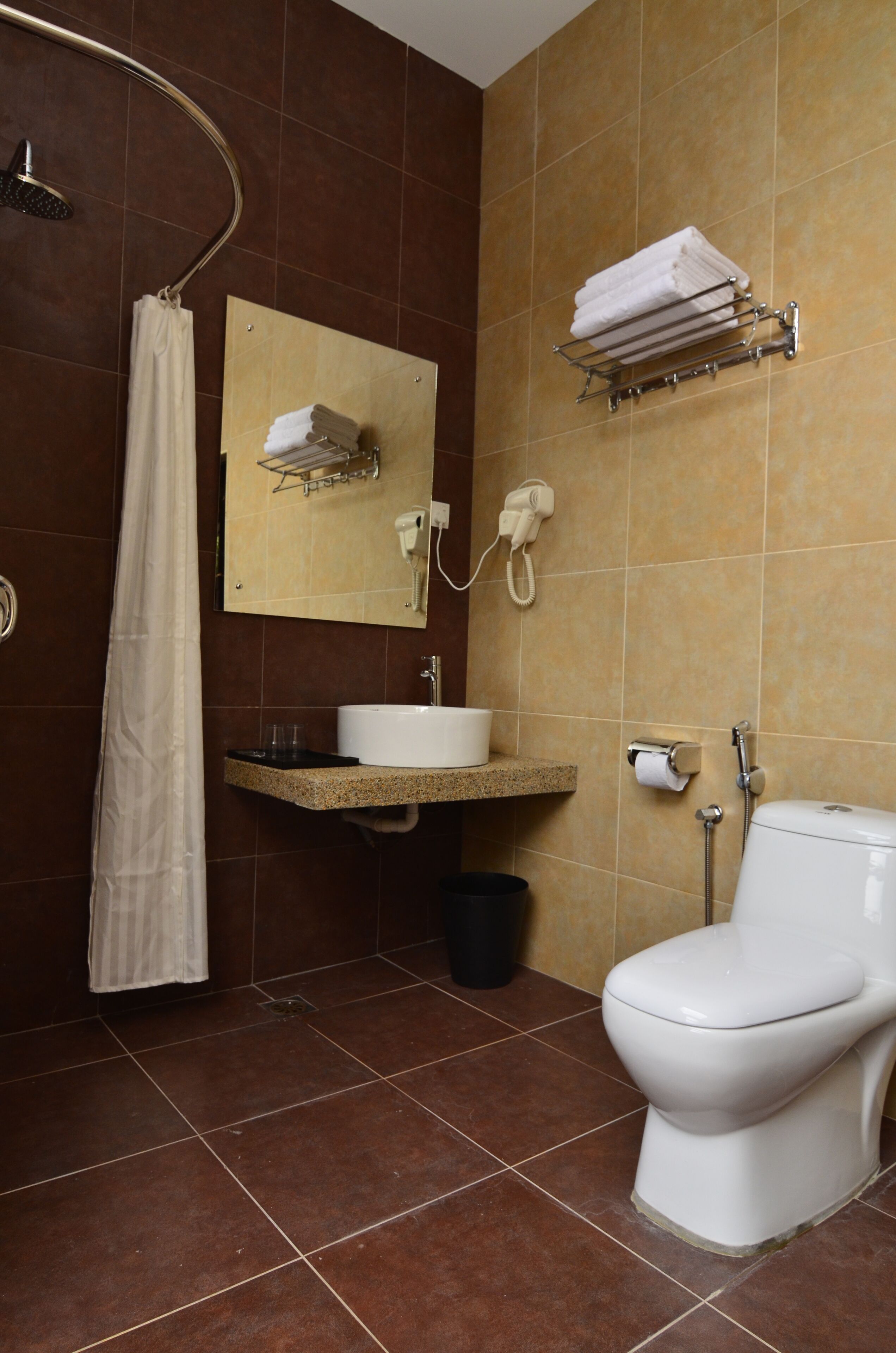 Un baño con ducha, lavabo, inodoro y perchero para toallas.