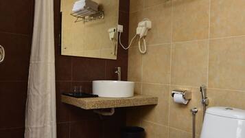 Un baño con ducha, lavabo, inodoro y perchero para toallas.