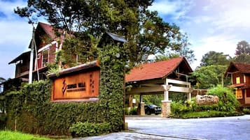 A rustic lodge with a wooden signboard, a covered entrance, and a welcoming sign.