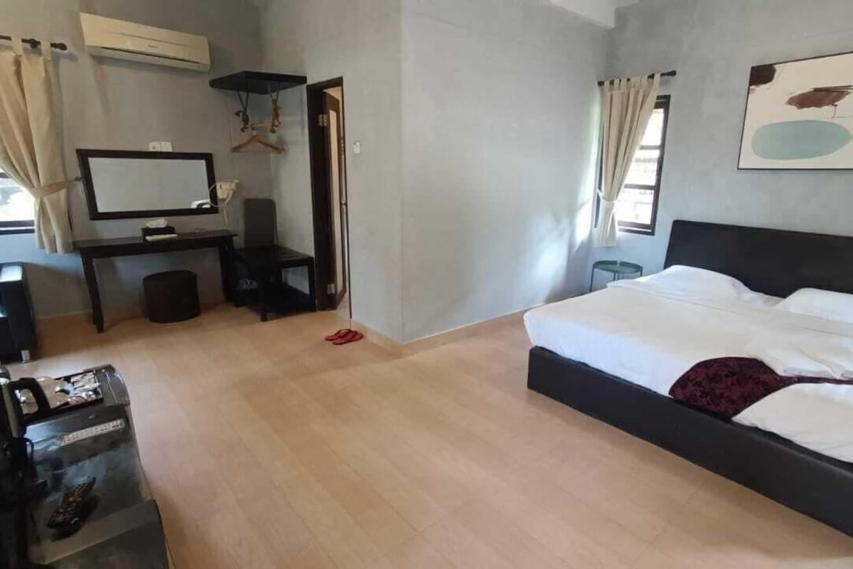 A bedroom with a bed, a desk, a chair, a TV, and an air conditioning unit.
