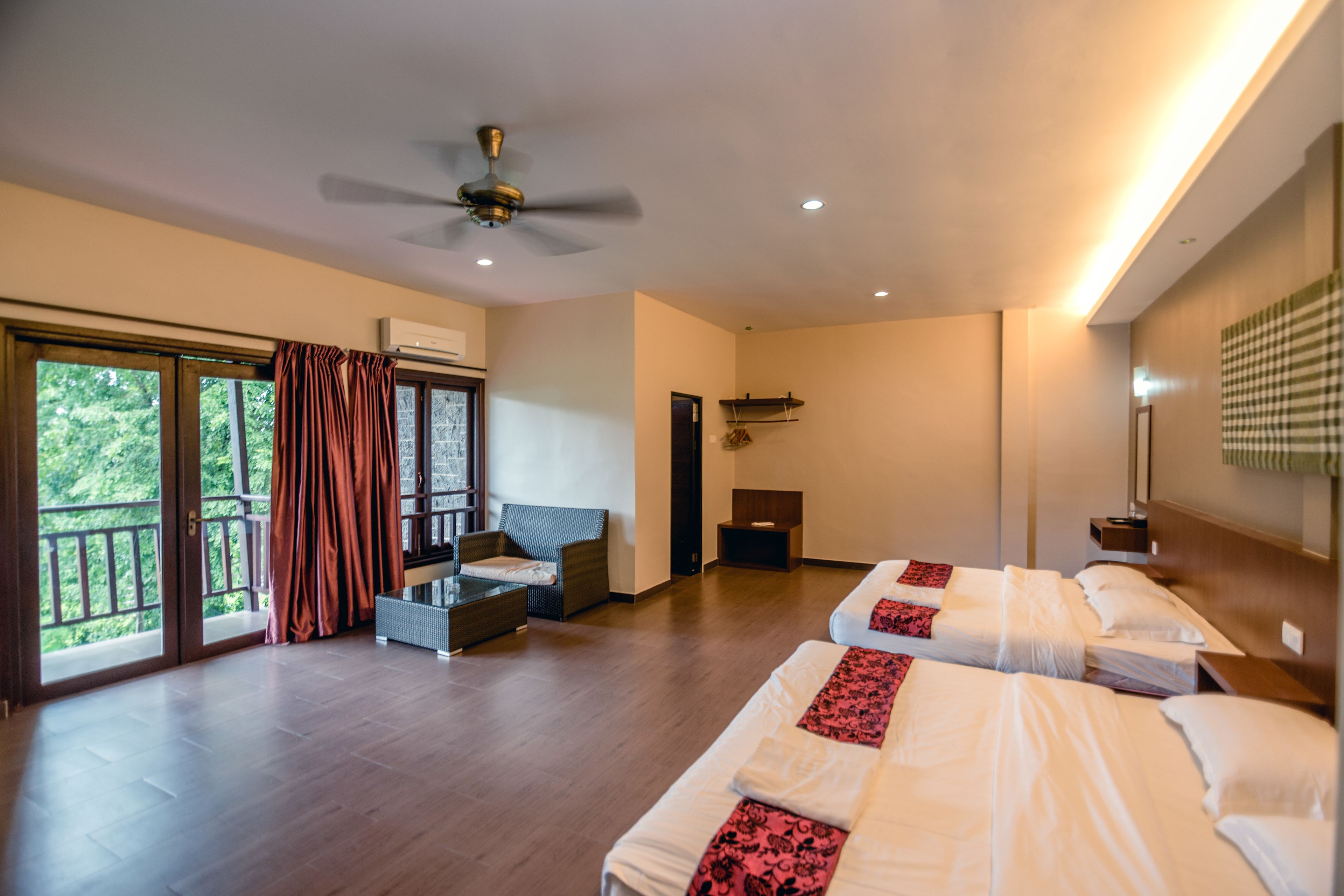A hotel room with two beds, a balcony, a ceiling fan, and a large window.