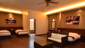 A hotel room with two single beds, a sofa, a coffee table, and a ceiling fan. - Sentosa Villa (Taiping)