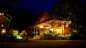 A wooden building with a sloped roof and a covered porch, surrounded by lush greenery. - Sentosa Villa (Taiping)