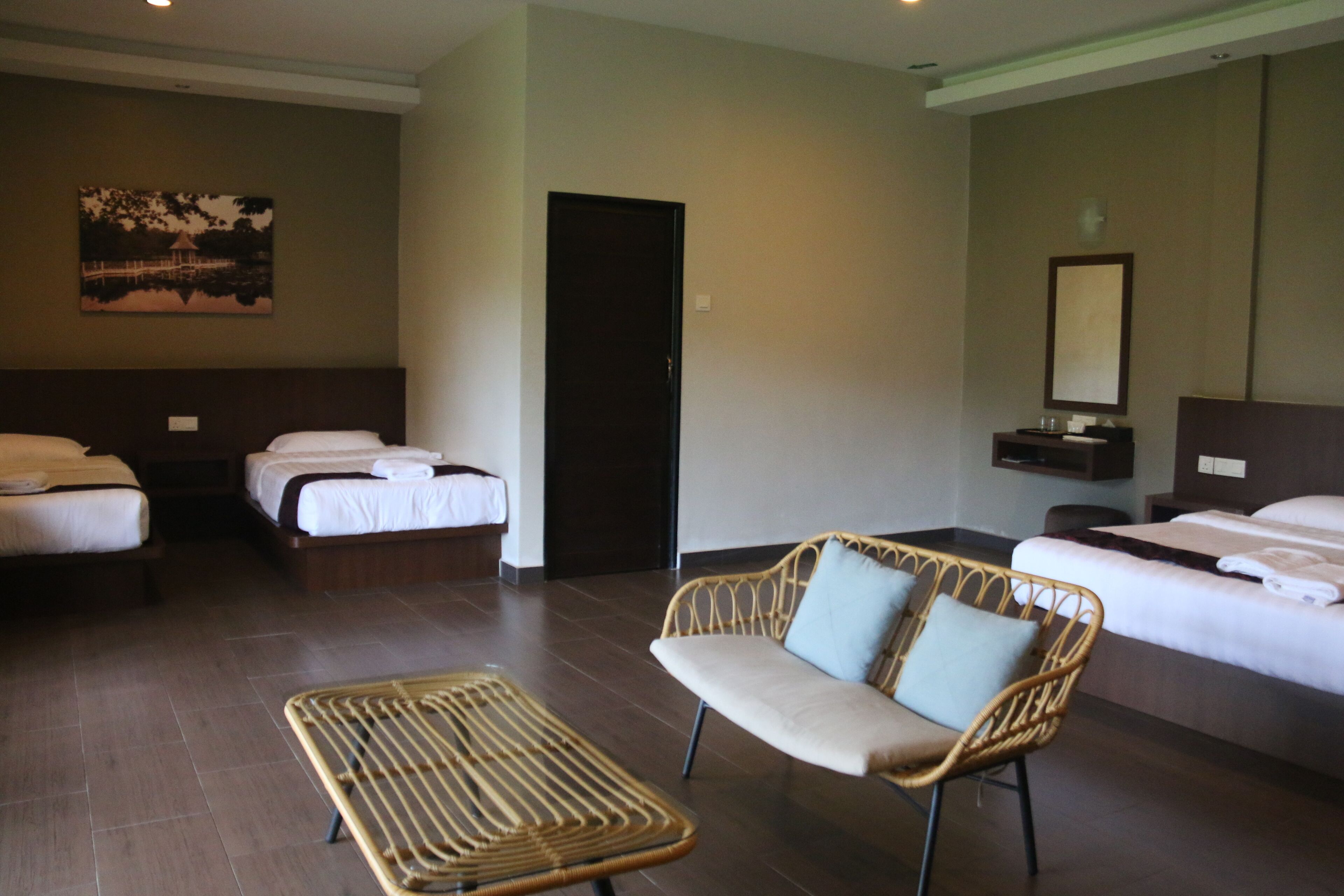 A hotel room with two beds, a sofa, a small table, and a painting on the wall.