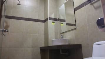 Een badkamer met een douche, wastafel, spiegel en toilet.