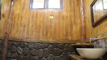 A wooden wall with a stone base, a window, and a white sink.