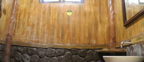 A wooden wall with a stone base, a window, and a white sink.