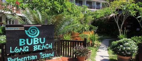 A sign for Bubu Long Beach Perhentian Island, surrounded by lush greenery and a wooden deck.
