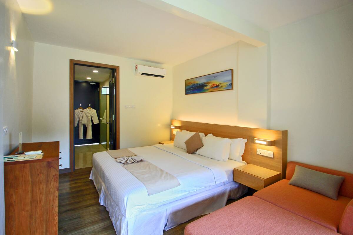 A hotel room with a bed, a desk, and a painting on the wall.