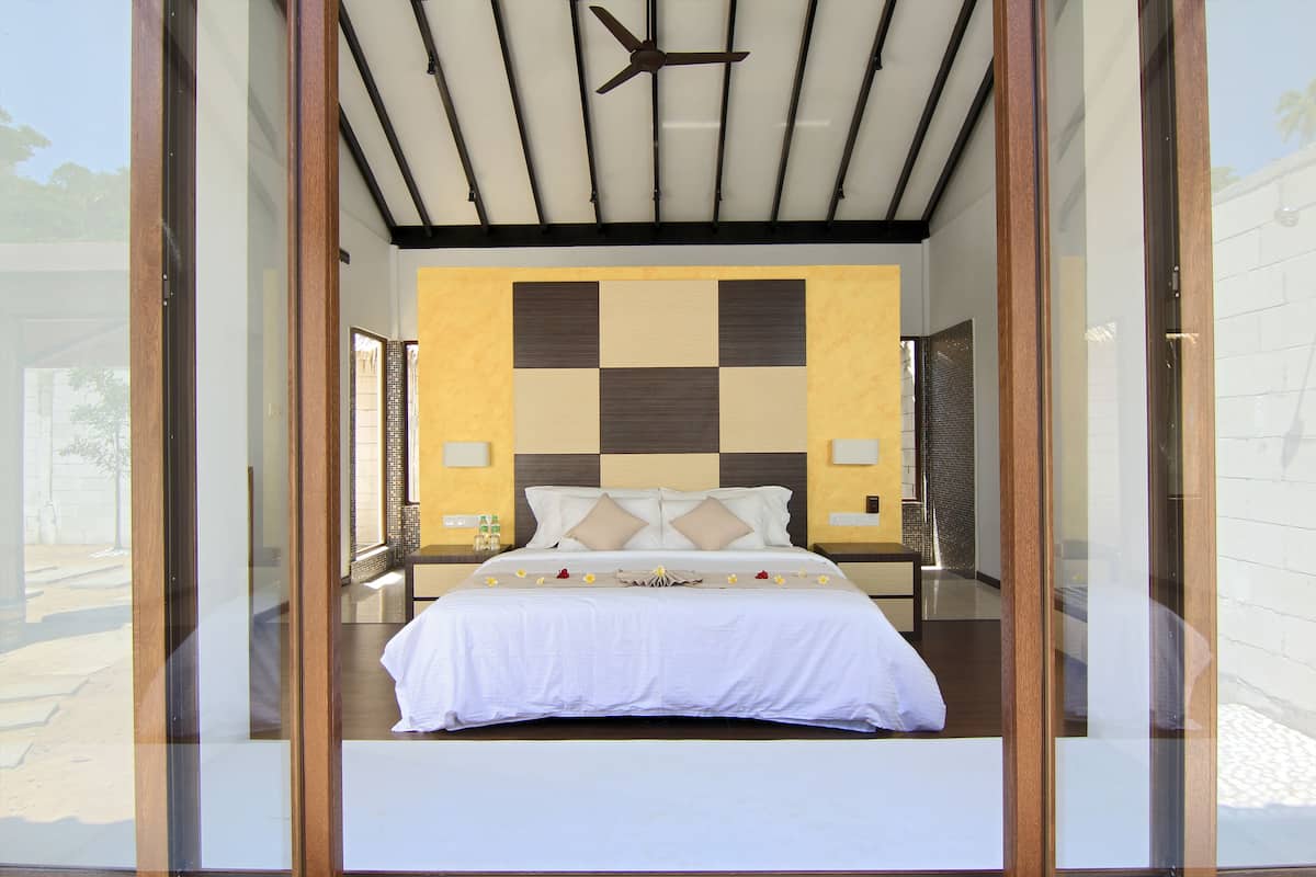 Een moderne hotelkamer met een groot bed, een plafondventilator en een geruit wandontwerp.