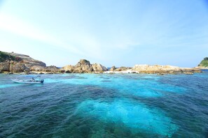 Une zone côtière caractérisée par des eaux turquoise et limpides, des formations rocheuses et un petit bateau.