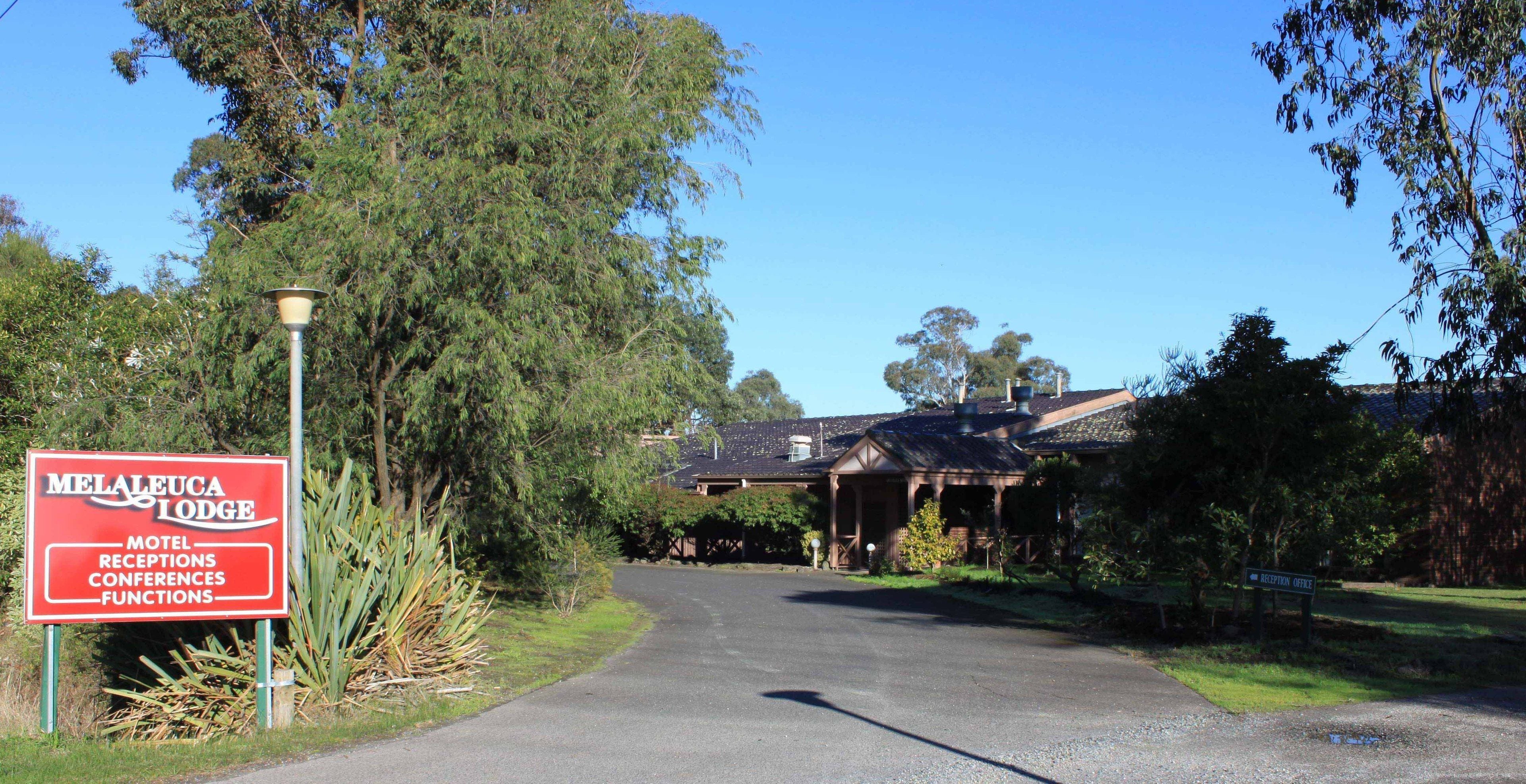 A red sign for Melaleuca Lodge indicating it is a motel, receptions, conferences, and functions.