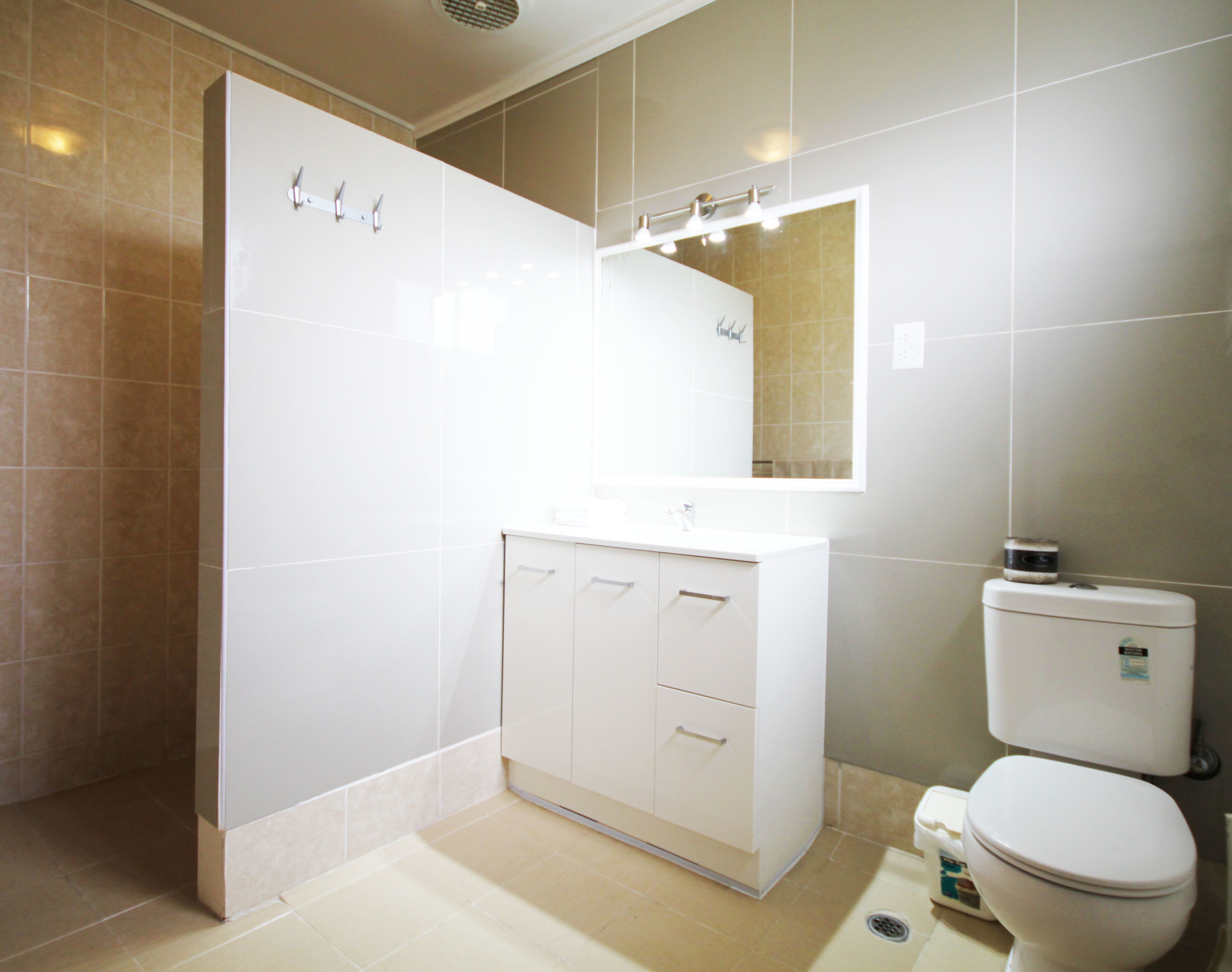 Une salle de bain moderne avec un meuble-lavabo blanc, un miroir et des toilettes.