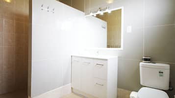 Une salle de bain moderne avec un meuble-lavabo blanc, un miroir et des toilettes.