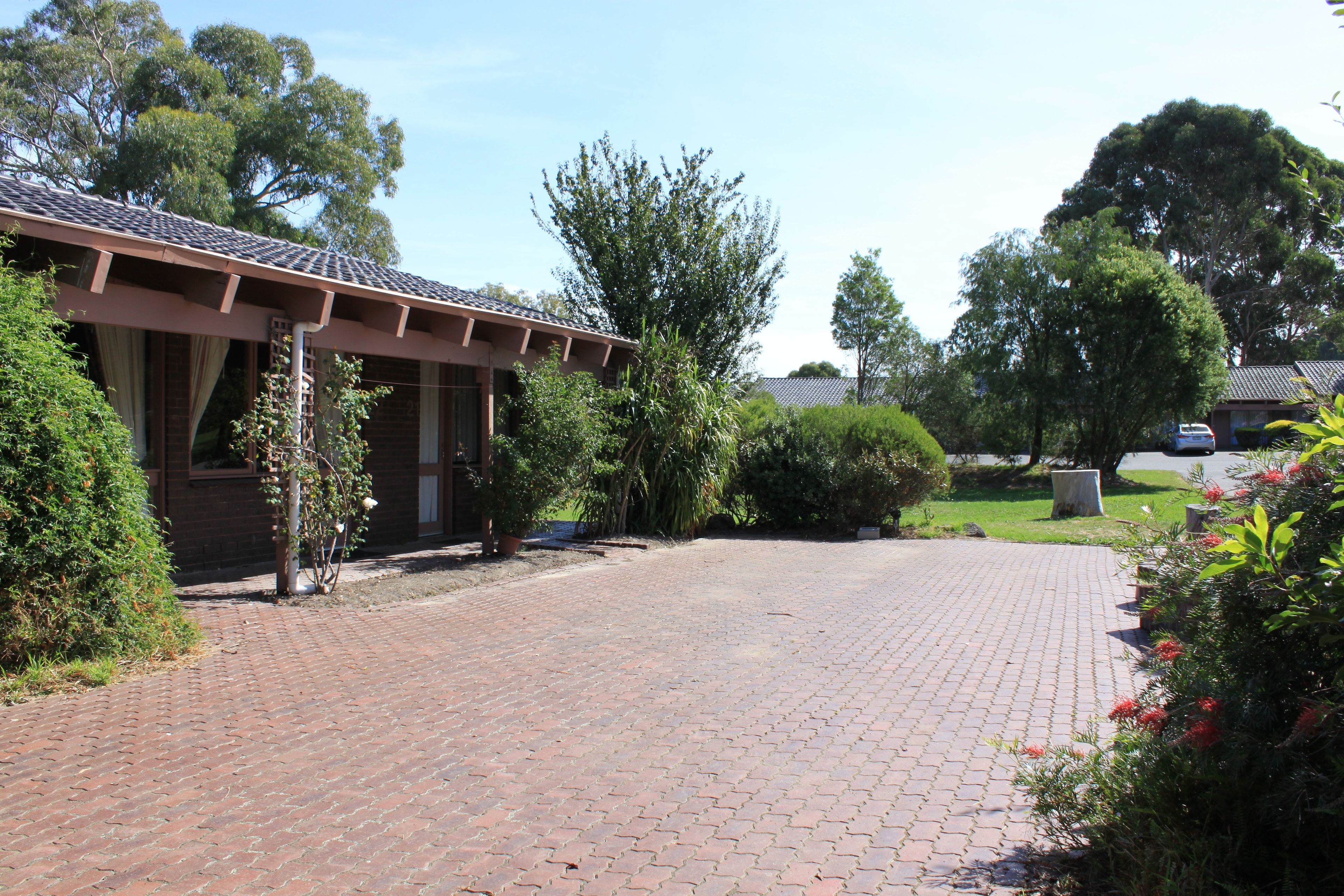 A paved driveway leading to a building with a tiled roof and brick walls.