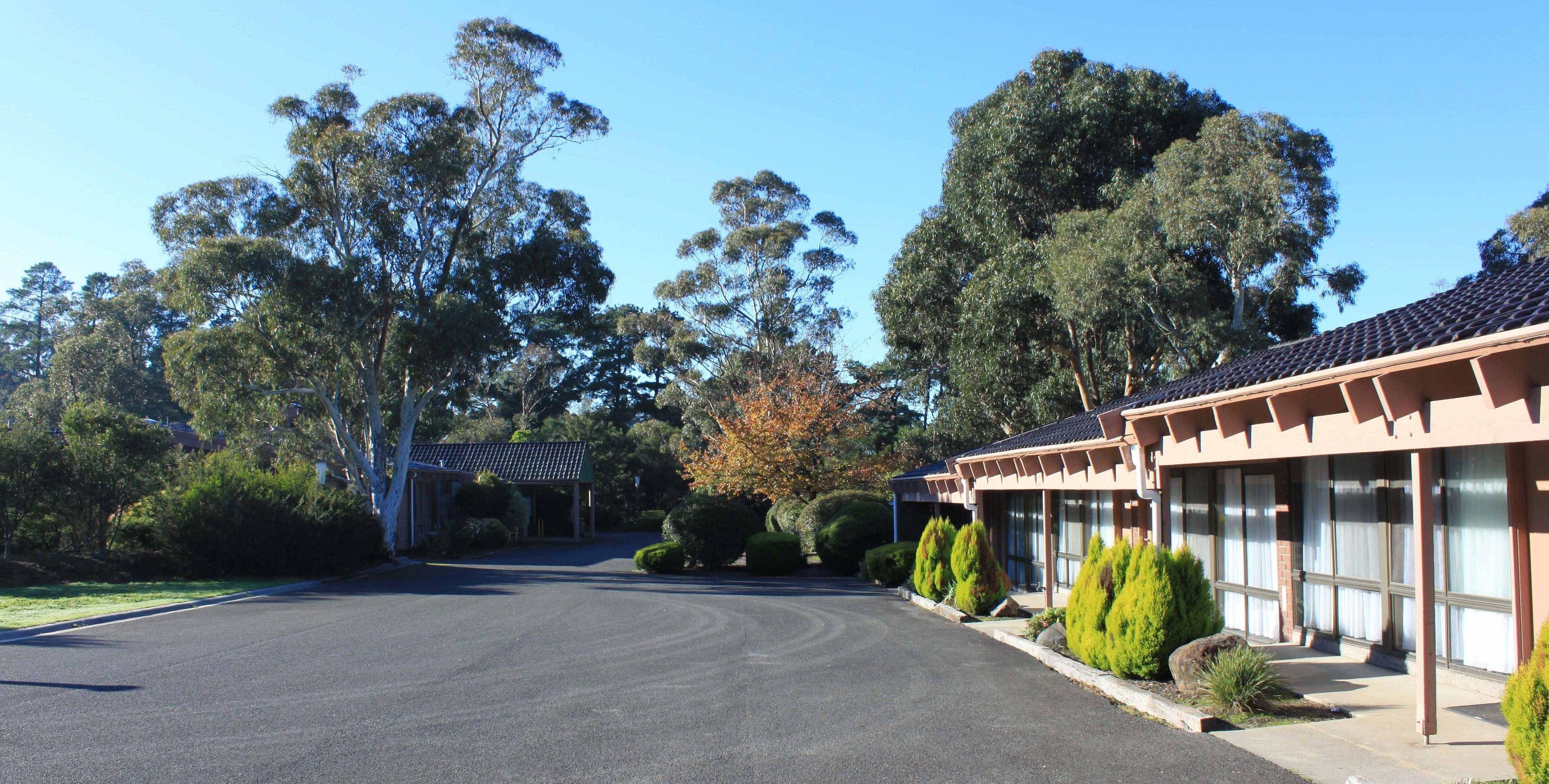 A building with a covered entrance, surrounded by trees and a clear sky.