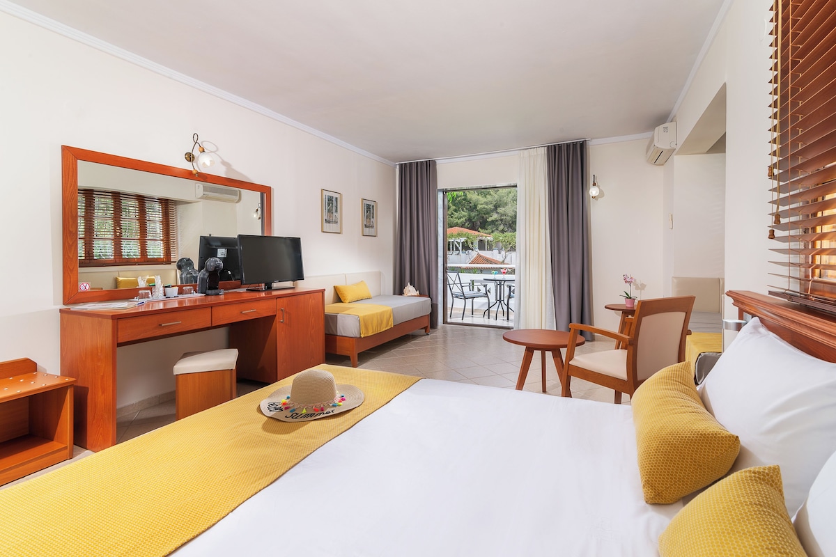 Una habitación de hotel con cama, escritorio, silla y vista al exterior.