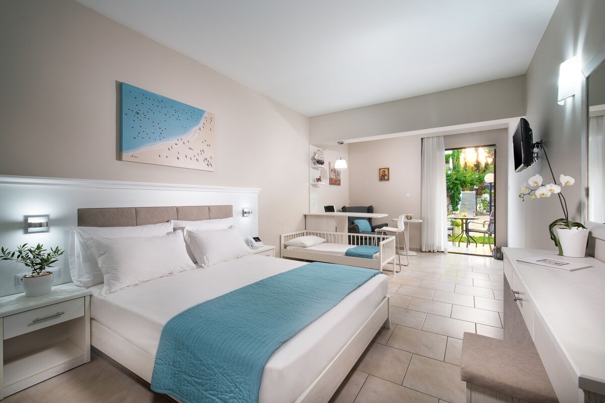 Un dormitorio moderno con una cama grande, mesitas de noche, un escritorio y vistas al exterior.