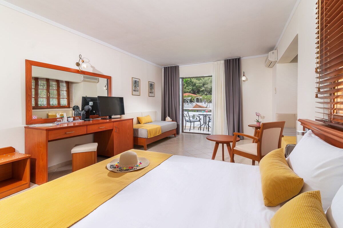 Una habitación de hotel con cama, escritorio, silla y vista al exterior.