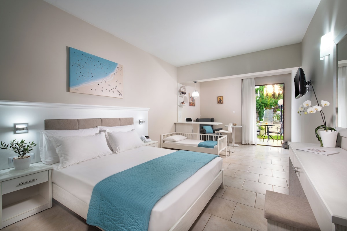 Un dormitorio moderno con una cama grande, mesitas de noche, un escritorio y vistas al exterior.