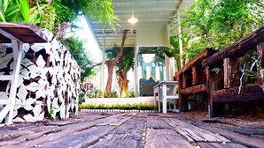A covered walkway with wooden flooring, surrounded by lush greenery and a white decorative wall. - Hy Resort (Chonburi)