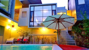 A modern outdoor pool area with a glass balustrade, a white umbrella, and a red brick pathway. - Hy Resort (Chonburi)