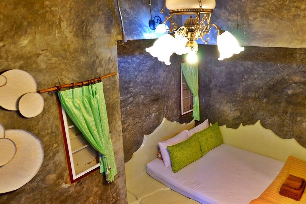 Un dormitorio acogedor con cama, lámpara colgante y ventana con cortinas verdes.