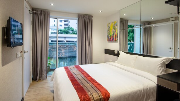 A modern hotel room with a large bed, a flat-screen TV, a large window with curtains, and a view of the outside. - 12FLY Hotel (Kuala Lumpur)