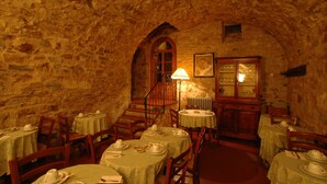 A stone-walled room with tables set for dining, a staircase, and a lamp. - Albergo Il Colombaio (Castellina in Chianti)