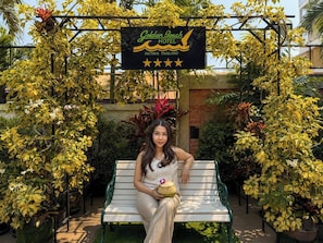 A woman sitting on a bench in front of a sign for Golden Beach Hotel in Pattaya, Thailand. - Golden Beach Hotel Pattaya (Pattaya)