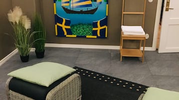 Una habitación con dos sofás de mimbre, un cuadro de un velero, una escalera y una puerta.
