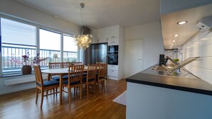Een moderne keuken met houten vloeren, een eethoek met een tafel en stoelen, en een groot raam met uitzicht.
