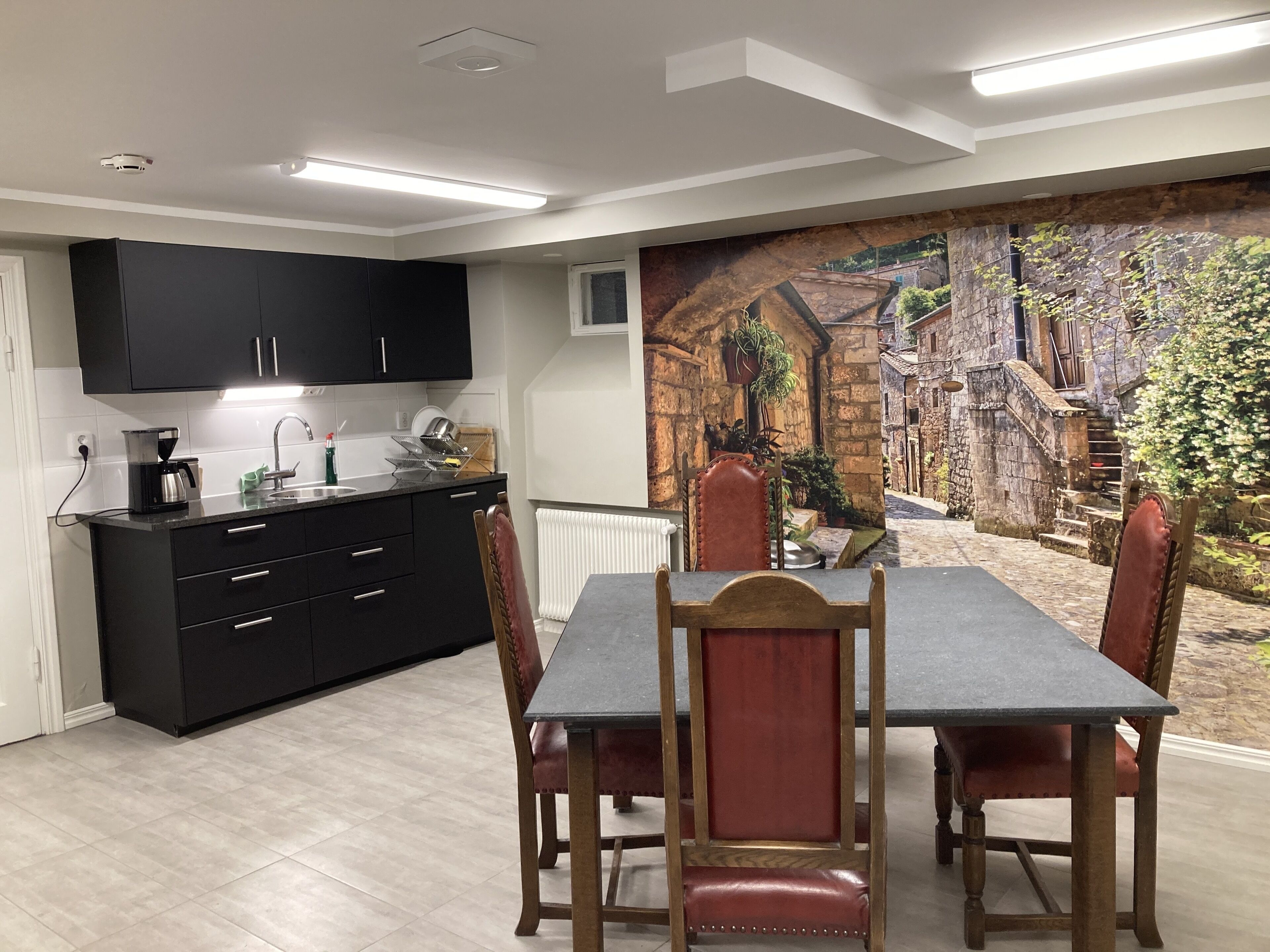 A modern kitchen with black cabinets and a dining area with a table and chairs.