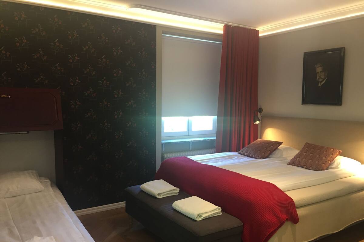 A hotel room with a bed, a bench, and a window.