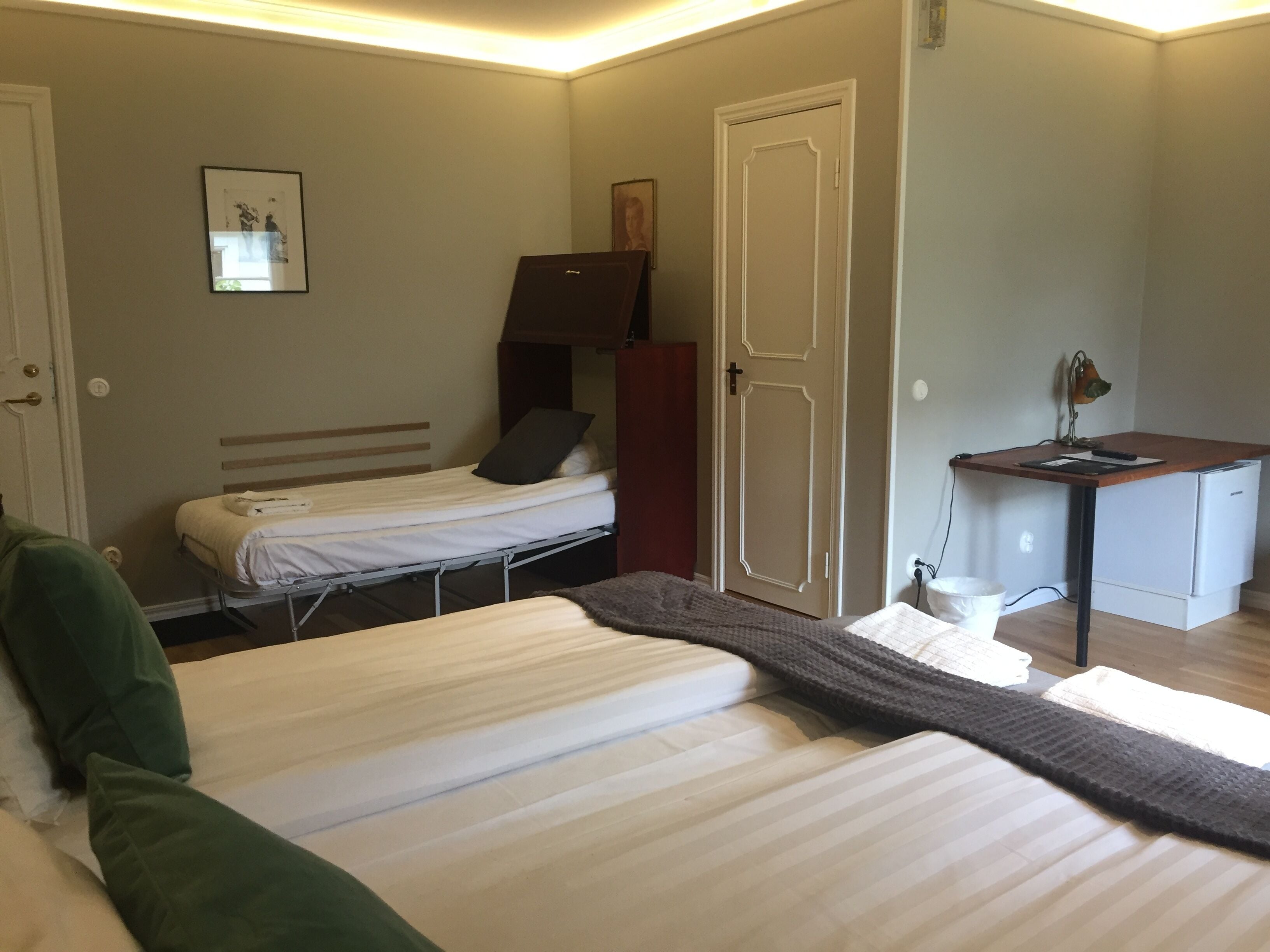 A small, neatly arranged bedroom with a bed, a desk, and a wardrobe.