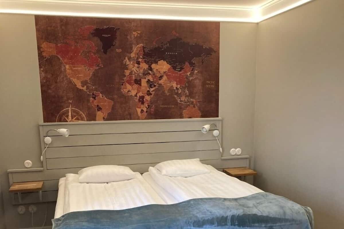A modern bedroom with a large bed, a headboard with integrated lighting, bedside tables, and a large abstract wall art piece.